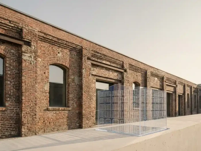 Transparant architectuurmodel op betonnen richel voor verweerde bakstenen gevel in zacht ochtendlicht