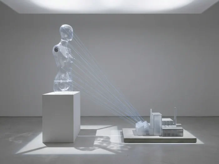 Transparante acryl mannequin op witte sokkel verbonden met laserdraden naar fabrieksmodel, minimalistische studio-opzet